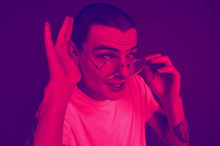 Listening to secret. Close up portrait of caucasian man isolated on studio background. Modern and...