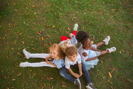 Dream team. Interracial group of kids, girls and boys playing together at the park in summer day....