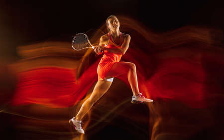 High jump. Professional female tennis player training isolated on black studio background in mixed...