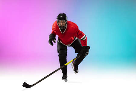 Winner. Male hockey player with the stick on ice court and neon gradient background. Sportsman wearing equipment, helmet practicing. Concept of sport, healthy lifestyle, motion, wellness, action.の写真素材