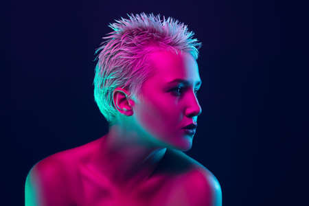 Shiny. Portrait of female fashion model in neon light on dark studio background. Beautiful caucasian woman with trendy make-up and well-kept skin. Vivid style, beauty concept. Close up. Copyspaceの写真素材