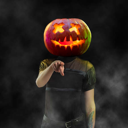 Young woman pointing headed by pumpkin on black background. Copyspace for your ad. Modern design. Contemporary artwork, collage. Concept of Halloween, Night of fear, trick or treat, jack-o-lanternsの写真素材