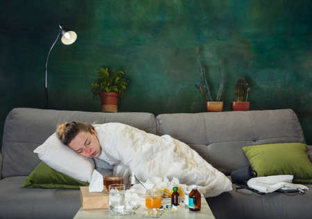 Honey and tea. Ill young girl with fever and cold feeling sick, blue, snuffling. Looks suffering and...