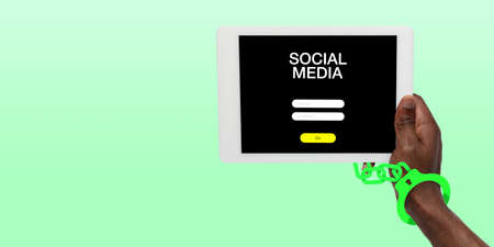 Hand using tablet, device on top view. Addicted man, wired with chain to social media on the screen with login frame. Technologies, modern, marketing, online. Green color on background. Flyerの写真素材
