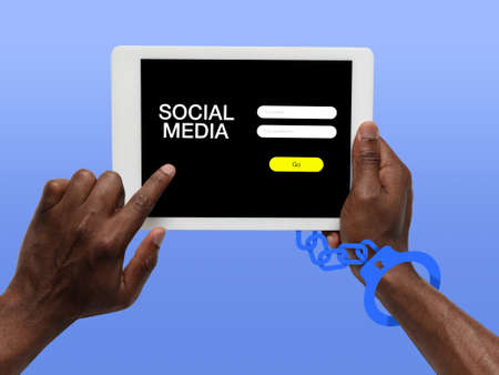 Hand using tablet, device on top view. Addicted man, wired with chain to social media on the screen...