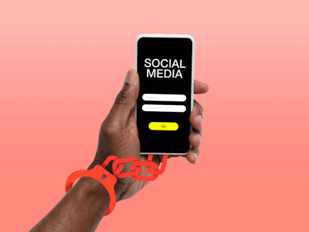 Hand using smartphone, device on top view. Addicted man, wired with chain to social media on the screen with login frame. Technologies, modern, marketing, online. Coral color on background.の写真素材