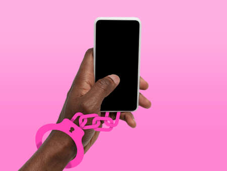 Hand using phone, device on top view. Addicted man, wired with chain to social media or games...