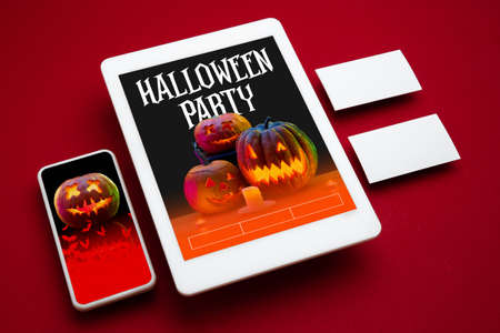 Scary pumpkin on device screen and red background. Jack-o-Lanterns with candles. Halloween, black friday, cyber monday, sales, party, autumn concept. Tablet and money card. Invite cards, promotion.