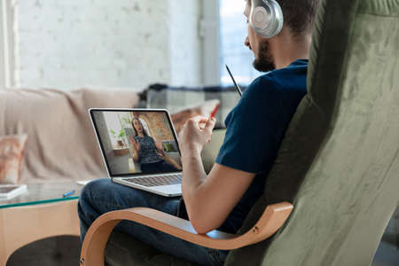 Man working from home, using devices, remote office concept. Young businessman, manager doing tasks...