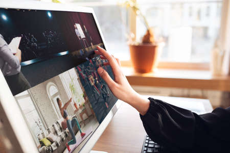 Woman choosing what to watch at home during insulation, COVID-19 quarantine. Close up of female hand scrolling screen to choose online education, cinema, concert or meeting. Devices, tech and gadgets.の写真素材