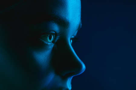 Look. Portrait of female fashion model in neon light on dark studio background. Beautiful caucasian woman with trendy make-up and well-kept skin. Vivid style, beauty concept. Close up. Copyspaceの写真素材