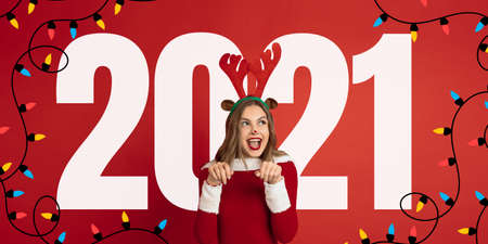Emotional Santa Claus deer greeting with New Year 2021 and Christmas. Beautiful woman in red costume. Concept of holidays and winter mood. Flyer with cpyspace. Stylish senior with nice signの写真素材