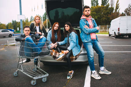 Rebel. Group of four young diverse friends in jeanse outfit look carefree, young and happy walking down the citys streets. Fashion of urban clothes, freedom, friendship, style concept.の写真素材