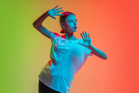 Framing. Young caucasian girls portrait on gradient green-orange studio background in neon light....