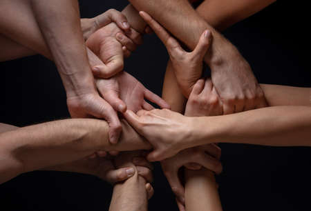 Stopping. Hands of peoples crows in touch isolated on black studio background. Concept of human relation, community, togetherness, symbolism. Hard and strong touching, creating one unit.の写真素材