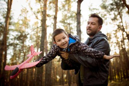 Emotions. Father and son walking and having fun in autumn forest, look happy and sincere. Laughting,...