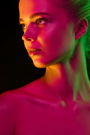 Skin glow. Portrait of female fashion model in neon light on dark studio background. Beautiful caucasian woman with trendy make-up and well-kept skin. Vivid style, beauty concept. Close up.の写真素材