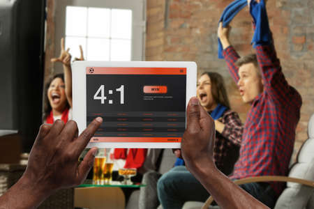 Device screen with mobile app for betting and score. Device with match results on screen, excited...