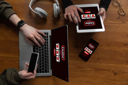 Close up laptop and smartphone screen with mobile app for online casino lottery. Male hands holding devices with game results on screens. Gambling, betting, sport, finance, modern technologies concept.の写真素材