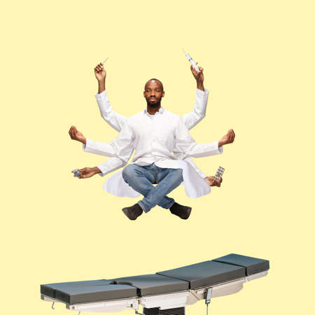 Handsome african doctor, multi-armed man levitating isolated on yellow studio background with equipment. Concept of professional occupation, work, job, medicine, healthcare. Multi-task like Shiva.の写真素材