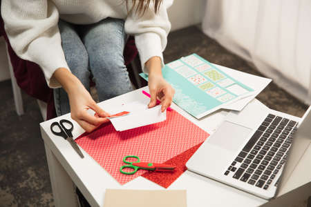 Close up female hands making greeting card for New Year and Christmas 2021 for friends or family, scrap booking, DIY. Writing a letter with best wishes, design her homemade card. Holidays, celebration.の写真素材
