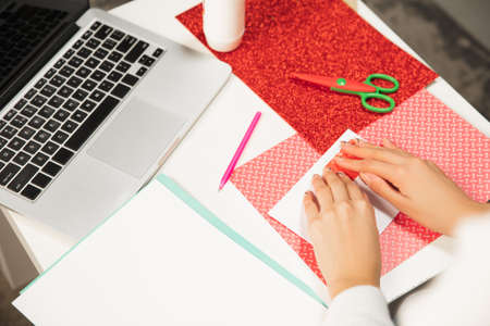 Close up female hands making greeting card for New Year and Christmas 2021 for friends or family, scrap booking, DIY. Writing a letter with best wishes, design her homemade card. Holidays, celebration.の写真素材