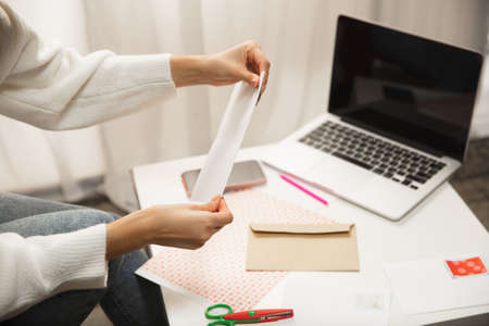 Close up female hands making greeting card for New Year and Christmas 2021 for friends or family, scrap booking, DIY. Writing a letter with best wishes, design her homemade card. Holidays, celebration.の写真素材