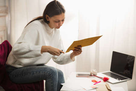 Comfortable. Woman opening, recieving greeting card for New Year and Christmas 2021 from friends or...