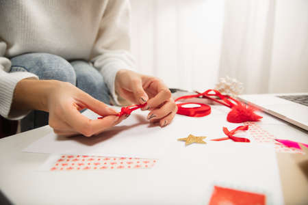 Close up female hands making greeting card for New Year and Christmas 2021 for friends or family, scrap booking, DIY. Writing a letter with best wishes, design her homemade card. Holidays, celebration.の写真素材