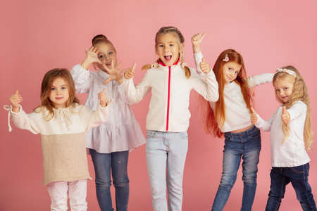 Thumbs up. Portrait of little caucasian children isolated on pink studio background with copyspace....