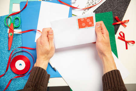 Close up male hands making greeting card for New Year and Christmas 2021 for friends or family, scrap booking, DIY. Writing a letter with best wishes, design his homemade card. Holidays, celebration.の写真素材