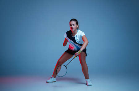Beautiful handicap woman practicing in badminton isolated on blue background in neon light. Lifestyle of inclusive people, diversity and equility. Sport, activity and movement. Copyspace for ad.の写真素材
