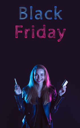 Beautiful woman inviting for shopping in black friday, sales concept. Vertical flyer. Cyber monday and online purchases, negative space for ad. Finance and money. Dark neon background with lettering.の写真素材