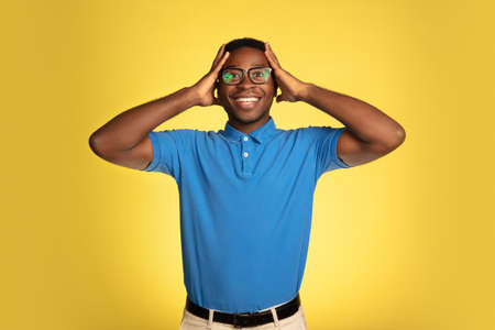 Astonished. Young african-american mans portrait isolated on yellow studio background, facial...