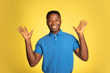 Wondered, surprised. Young african-american mans portrait isolated on yellow studio background,...