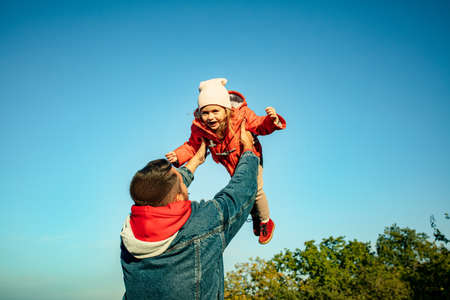 Flying high. Happy father and little cute daughter walking down the forest path in autumn sunny day....