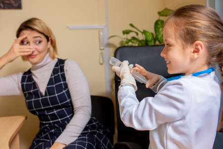 Little girl playing pretends like paediatrician doctor examining a patient in comfortabe medical...