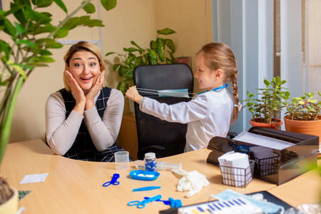 Little girl playing pretends like paediatrician doctor examining a patient in comfortabe medical...