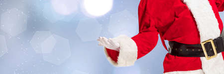 Greeting flyer for ad. Concept of Christmas, 2021 New Years, winter mood, holidays. Copyspace, postcard. Santa in traditional costume showing, pointing on blue bokeh background. Horizontalの写真素材