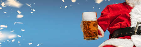 Greeting flyer for ad. Concept of Christmas, 2021 New Years, winter mood, holidays. Copyspace, postcard. Santa in traditional costume drinking beer isolated on blue bokeh background. Horizontalの写真素材