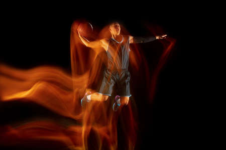 The fire tracks. Young east asian basketball player in action and motion jumping in mixed light over...