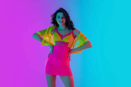 Smile. Beautiful seductive girl in fashionable bright crimson and yellow dress on gradient pink-blue...