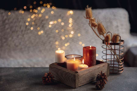 Candles in the wooden box isolated on grey white background. Garland lights. The concept of home atmosphere and comfort, holidays, romantic date, winter, home comfort, indoors, Christmas or New Year.の写真素材