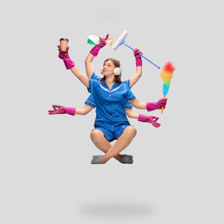 Female housemaid in blue uniform multitask like shiva isolated on gray background. Young woman chambermaid, maid with various household items. Professional occupation, time concept. Copyspace for ad.の写真素材