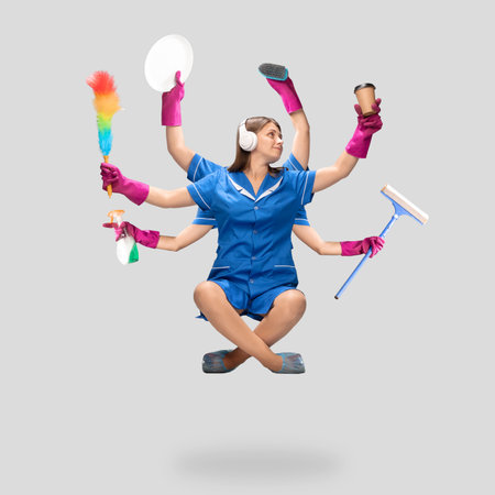 Music. Female housemaid in blue uniform multitask like shiva isolated on gray background. Young woman chambermaid with various items. Professional occupation, time concept. Copyspace for ad, design.の写真素材