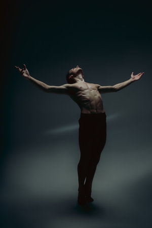 Inspiration. Young graceful male ballet dancer in minimal black style isolated on dark studio background. Art, motion, flexibility creation concept. Flexible caucasian ballet dancer. Copyspace for adの写真素材