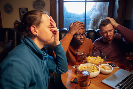 High tension. Excited fans in bar with beer and mobile app for betting, score on their devices. Screen with match results, emotional friends cheering. Gambling, sport, finance, modern techn concept.の写真素材
