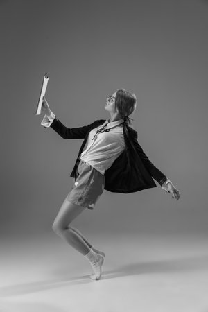 Weightless. Young fashionable, stylish woman wearing jacket and socks working from home. Fashion during insulation cause of coronavirus pandemic. Half business and half home style. Black and white.の写真素材