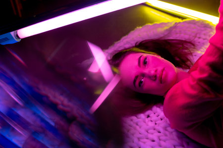 Stunning. Caucasian female inclusive model posing on studio background in neon light. Realness,...