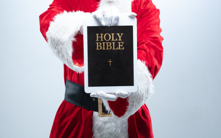 Close up hands of Santa Claus holding device with Holy Bible on the screen. Concept of winter sales, New Year 2021 and Christmas celebration, modern device and gadgets, online shopping.の写真素材